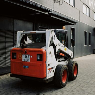 Modern small truck parked near warehouse on street in city