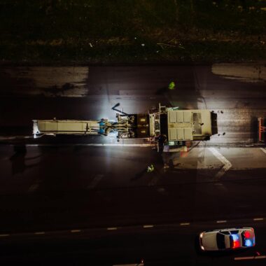 Top view of specialized vehicles with lights on repairing road and laying asphalt and concrete at night